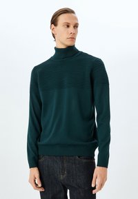 Mörk teal-ribbade turtleneck-tröja med en texturerad övre panel och slät nedre del, långa åtsittande ärmar och elastisk midja.