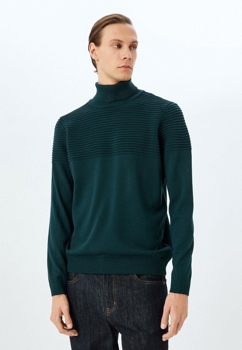 Mörk teal-ribbade turtleneck-tröja med en texturerad övre panel och slät nedre del, långa åtsittande ärmar och elastisk midja.