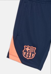 Tamno plave sportske kratke hlače s koraljnim bočnim panelima i izvezelim grbom FC Barcelone na donjem prednjem dijelu.