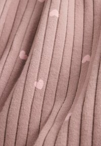 Close-up of ribbed pink fabric with small lighter pink heart patterns scattered across the surface.