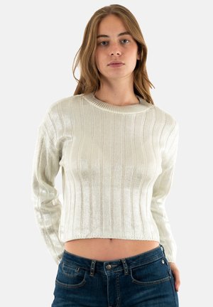 Maglione bianco a costine con scollatura rotonda e maniche lunghe, caratterizzato da una texture lucida. Indossato con jeans aderenti blu scuro.