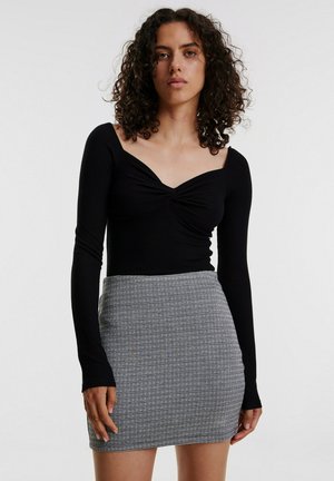 Black long-sleeve top with a sweetheart neckline, paired with a fitted skirt featuring a black and white checkered pattern.