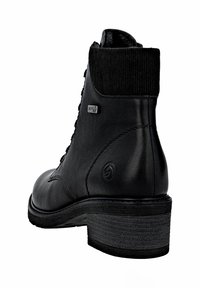 Bota negra de cuero liso con un cuello de punto acanalado y un tacón apilado. Presenta un cierre de cordones en la parte delantera y un detalle de marca a prueba de agua.