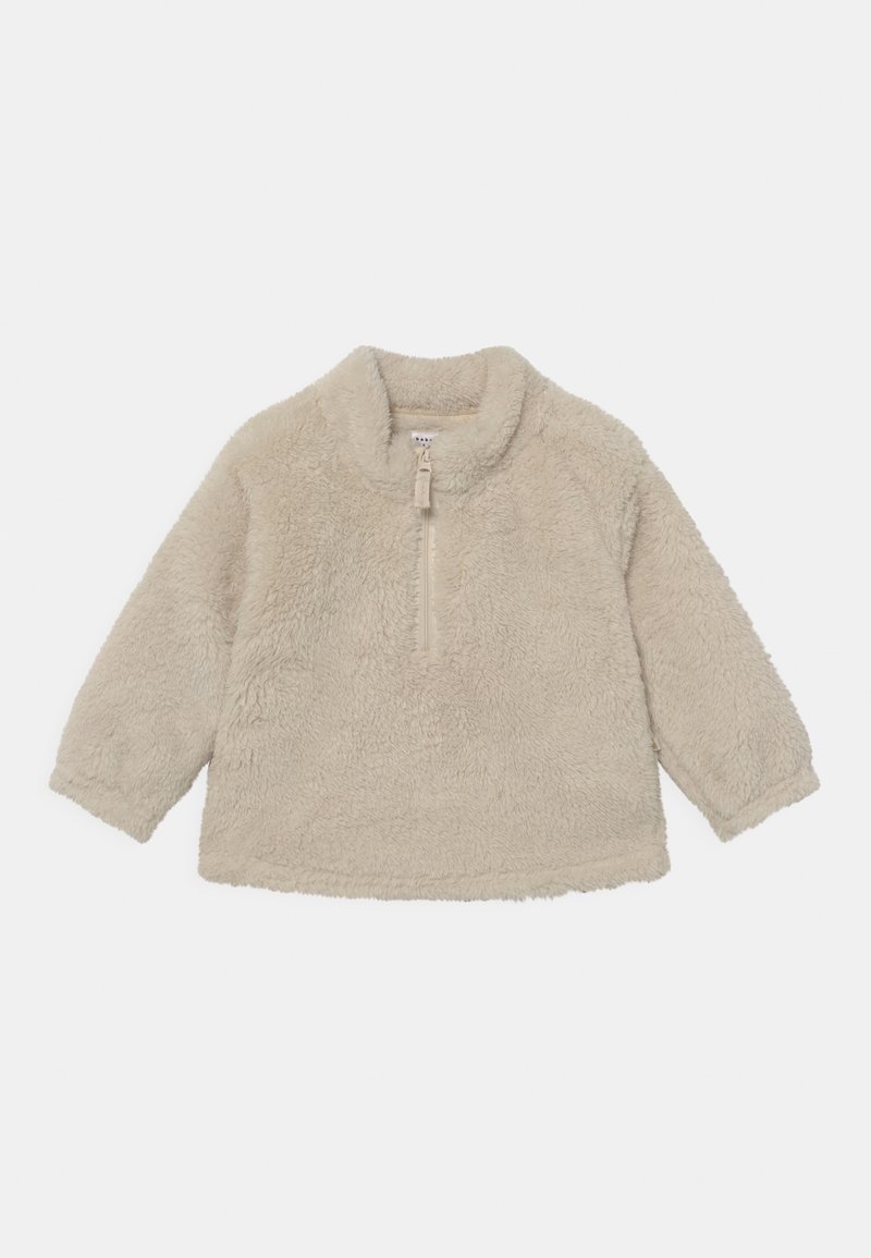 Pull polaire beige à manches longues avec col montant et fermeture éclair mi-longue au centre devant.