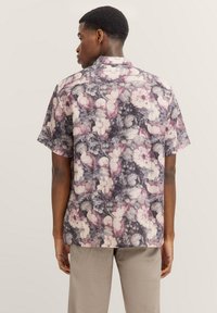 Kurzärmliges Blumenshirt mit lila und cremefarbenem Muster, aus leichtem Stoff gefertigt, mit geradem Saum und klassischem Kragen.