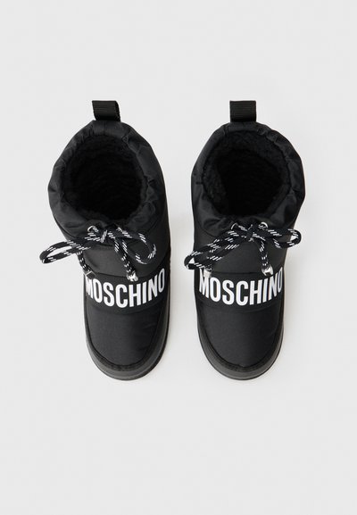 Melni auduma zābaki ar mīkstu iekšpusi, aprīkoti ar baltu "MOSCHINO" zīmolu, melnbaltām šņorēm un cilpu aizmugurē.