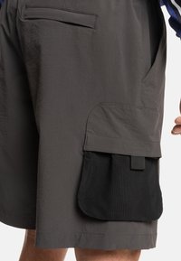 Grijze shorts van een textuurstof, met een zijflapzak van zwart gaas. Bevat een schuin voorvak en een gestikte zoom.