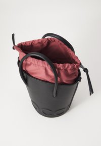 Black textured leather bucket bag with a gathered burgundy fabric lining. Features two black leather handles and a drawstring closure.