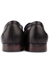 Black leather shoes with a textured surface, rounded back, and wooden heel. The design is sleek with subtle stitching accents.