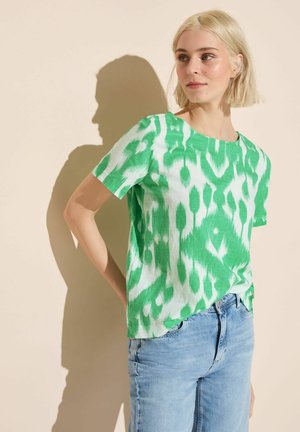 Top corto a maniche corte verde e bianco con scollatura rotonda. Realizzato in tessuto leggero, presenta un design astratto in stile tie-dye.