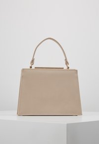 Beżowa torebka z gładkiej skóry o usztywnionym fasonie, z krótkim uchwytem i złotymi elementami. Kanciasty kształt z przeszywanymi akcentami.