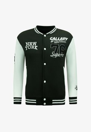 Zwart-witte varsity jack met geborduurde tekst, knopen en gestreepte ribbels. Heeft ontwerpen van "NEW YORK" en "76". Gladde textuur.