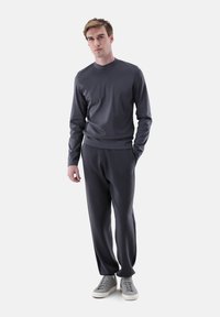 Graues Sportbekleidungsset mit langärmligem Oberteil mit Rundhalsausschnitt und passenden, zulaufenden Hosen, beide aus weichem Stoff gefertigt.