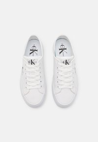 Sneaker bianche in tela con punte rotonde, lacci piatti e suole in gomma. Presentano solette con marchio e accenti con logo sul lato.