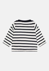Blusa de mangas longas em tecido de malha listrado em branco e azul-marinho. Apresenta um decote redondo e um corte descontraído. Textura suave, design simples, sem adornos.