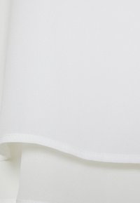 Witte stof met een zachte textuur en een lichte glans, met strakke, rechte randen en een subtiel gevouwen ontwerp.