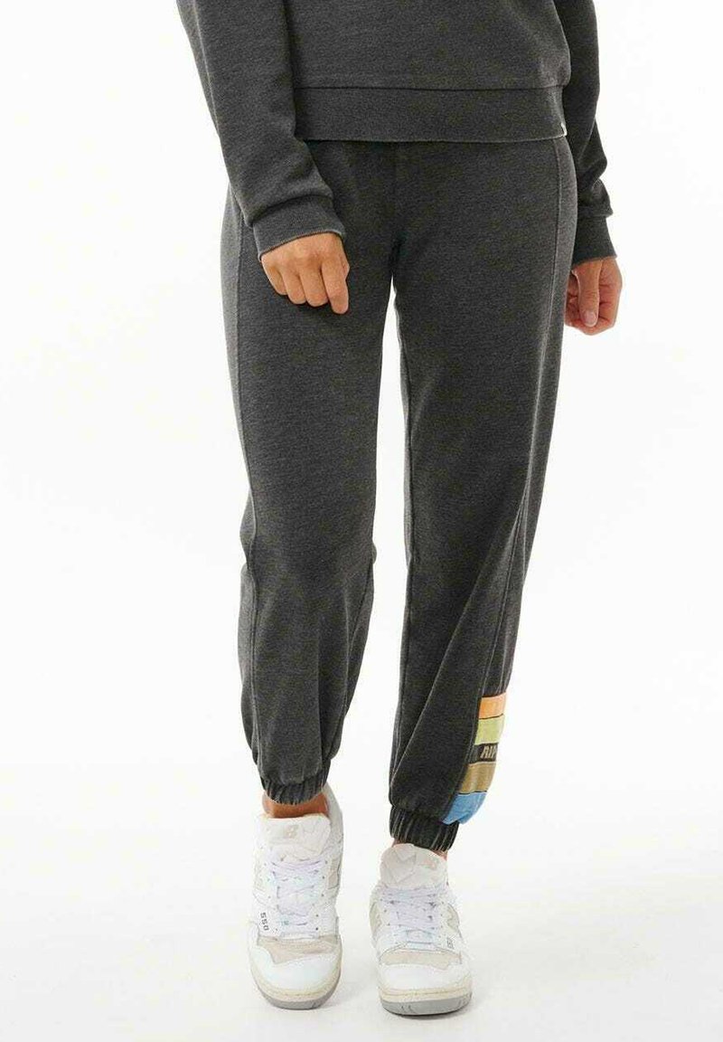 Grå sweatpants med elastiske manchetter og en farverig stribet detalje på underbenet. Materialet ser blødt og åndbart ud, hvilket gør dem velegnede til afslappet brug.