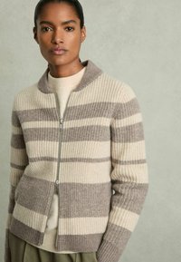 Beige och brunrandig cardigan med ribbat mönster, långärmade ärmar och dragkedjestängning. Mjuk ullblandning och kragdesign.