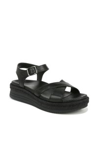 Black leather sandal with crisscross straps, adjustable buckle, and a thick braided platform sole. Textured footbed for added comfort.