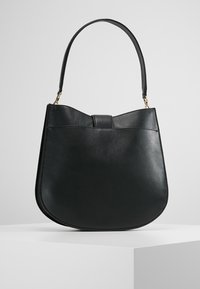 Czarna skórzana torebka o zaokrąglonym kształcie, z pojedynczym paskiem na ramię i klapą zapiętą na zatrzask, ozdobiona elementami w złotym odcieniu.