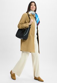 Light brown trench coat, white top, cream wide-leg pants, tan loafers, and a black handbag. Colorful silk scarf around the neck.
