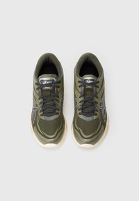 Zaļi sintētiskie sporta apavi ar teksturētu virsmu, pelēkiem akcentiem, melniem šņorēm un mīkstu zoli. Izstrādāti komforta un atbalsta nodrošināšanai.