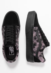 Schwarze Wildleder- und lila Pelzsneaker mit Plateausohle, versehen mit strukturiertem Material und schwarzen Schnürsenkeln. Akzente durch einen charakteristischen seitlichen Streifen.