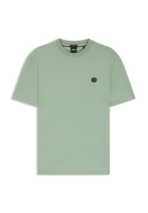 Ljusgrön bomulls-t-shirt med rund hals, korta ärmar och en liten svart logotypväska på bröstet. Mjuk textur med en enkel design.