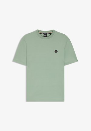 Ljusgrön bomulls-t-shirt med rund hals, korta ärmar och en liten svart logotypväska på bröstet. Mjuk textur med en enkel design.