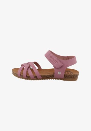 Sandale en simili cuir rose avec trois brides avant, une bride arrière, et une semelle en liège texturée. Dispose d'un accent métallique et d'un logo sur la bride.