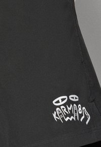 Schwarze Shorts mit glatter Textur und passgenauem Design. Auffällige weiße Grafik mit abstrakten Formen und dem Namen "Karma" am Saum.