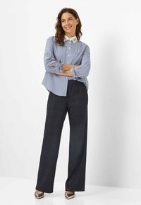 Blau-weiße gestreifte Hemdbluse mit einem weißen Kragen und Verzierungen, kombiniert mit navyblauen karrierten Weitbeinhosen und metallischen Absätzen.