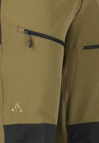Pantalons de sport verts avec des accents noirs, dotés de poches zippées et d'un tissu texturé. Logo doré affiché sur la cuisse.