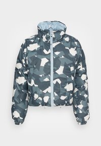 Doudoune à col montant, fermeture éclair intégrale à l'avant, avec un motif géométrique abstrait en gris, blanc et vert foncé.