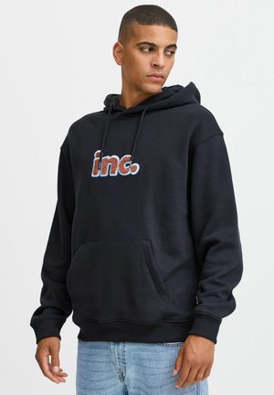 Schwarzer Hoodie aus einem weichen, strukturierten Material mit einer Fronttasche und Kapuze mit Kordelzug. "inc."-Logo in mehrfarbiger, strukturierter Stickerei.