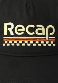 Căciulă neagră cu broderie "Recap" în crem, având dungi portocalii și un model în carouri sub text. Textura materialului este netedă.