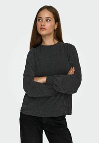 Top nero a maniche lunghe con righe verticali testurizzate, scollo rotondo e maniche a sbuffo, abbinato a pantaloni neri.