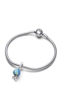 Srebrno plaščena zapestnica z tkanim dizajnom, ki vsebuje modri stekleni meduzni obesek z dvema prozornima akcentoma in zapiralom z logotipom.