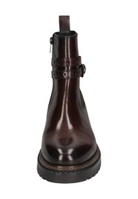 Braune Lederknöchelstiefel mit glatter Oberfläche, ausgestattet mit einem Riemen mit runden Ausschnitten, einer schwarzen Gummisohle und einem Zuglasche hinten.