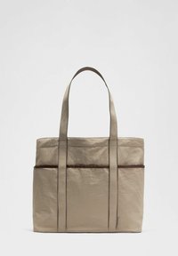 Bolso tote beige hecho de un tejido duradero, con dos asas largas, una superficie texturizada y una franja marrón contrastante en la parte delantera.