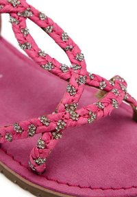 Sandalia rosa con tiras trenzadas adornadas con pequeños strass. Plantilla de ante rosa suave, suela flexible con un detalle de borde cosido.