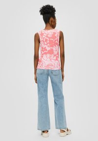 Mouwloze roze bloemen tanktop met een ontspannen pasvorm, gecombineerd met lichtblauwe wijde jeans en beige sandalen. Textuurstof met bloemenpatroon.