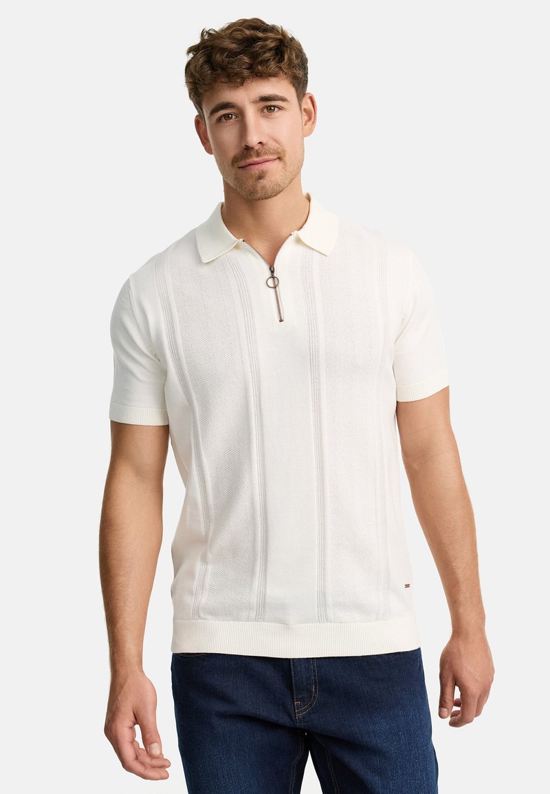 Camiseta polo de manga corta en color crema con cierre de cremallera, puños de canalé, rayas verticales texturizadas y un diseño ajustado.