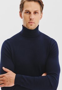 Granatowy sweter z golfem, wykonany z miękkiego dzianiny, z długimi rękawami i dopasowanym krojem wokół szyi i ciała.