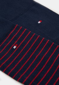 Navy socks featuring a horizontal striped pattern in red, with a solid section and a small logo in red, white, and blue.