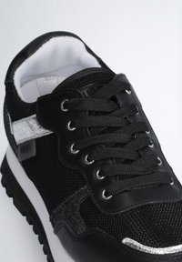 Scarpa sportiva nera con tomaia in rete e dettagli in pelle lucida. Presenta lacci rotondi, una striscia metallica e una suola in gomma testurizzata.