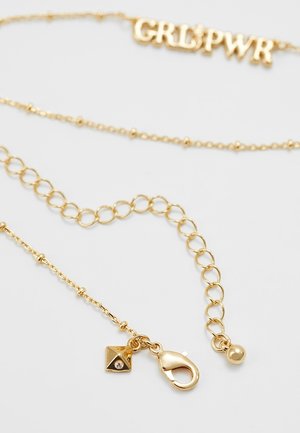 Goldene Halskette mit Karabinerverschluss, verstellbaren Gliedern und einem kleinen pyramidenförmigen Anhänger mit klarem Steinbesatz.