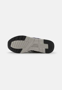 Shoe sole with a black and gray color scheme, featuring textured rubber for grip and molded patterns for traction and support.