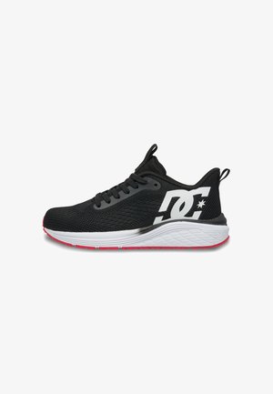 Sort atletiksneaker med hvid sål og rød bund, med stort hvidt DC-logo på siden og sorte snørebånd.