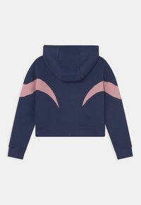 Námořnická modrá zkrácená mikina s kapucí, s růžovým abstraktním designem na rukávech, vyrobená z měkkého materiálu. Má kapucu a manžetové rukávy.